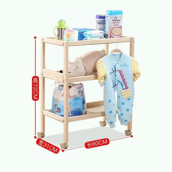 Baby care station with various items including a baby outfit, diapers in a wooden foldable bedside table..