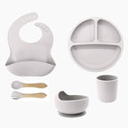 Set of gray baby feeding utensils including a bib, plate, cup, bowl, and spoons 