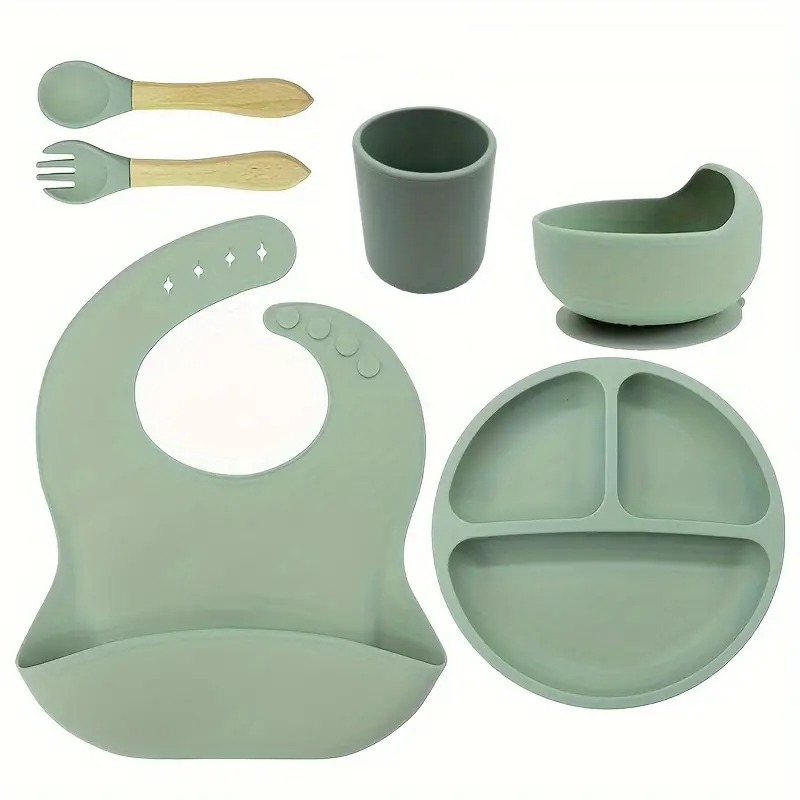 Set of green silicone baby feeding set including a bib, cup, bowl, and plate .