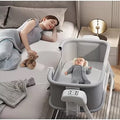 Woman lying on a bed with a baby in a portable crib 