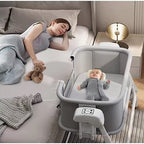 Woman lying on a bed with a baby in a portable crib 