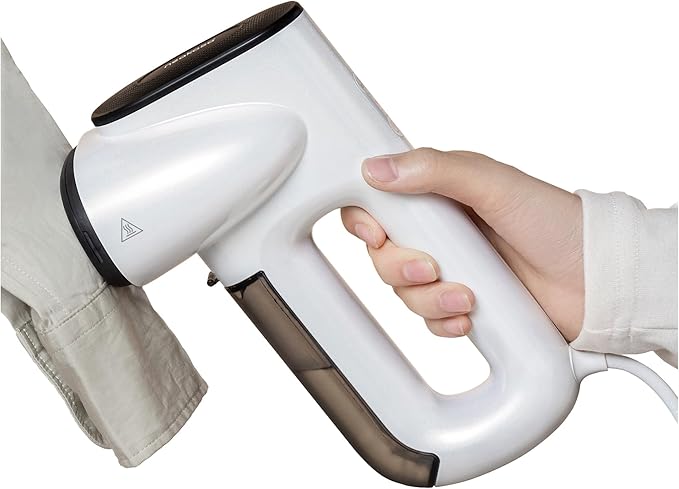 Hand holding a white  Neakasa handheld steamer over a piece of fabric 