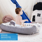 Baby  sitting on a geometric-patterned breathable baby portable crib.