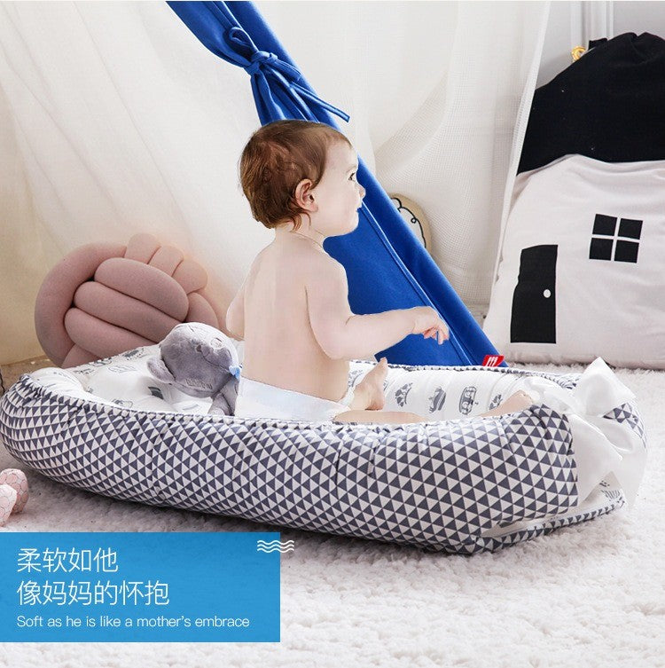 Baby  sitting on a geometric-patterned breathable baby portable crib.
