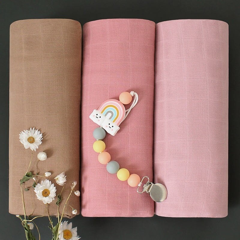 Three rolled-up swaddle in brown, pink, and light pink with a baby teether 