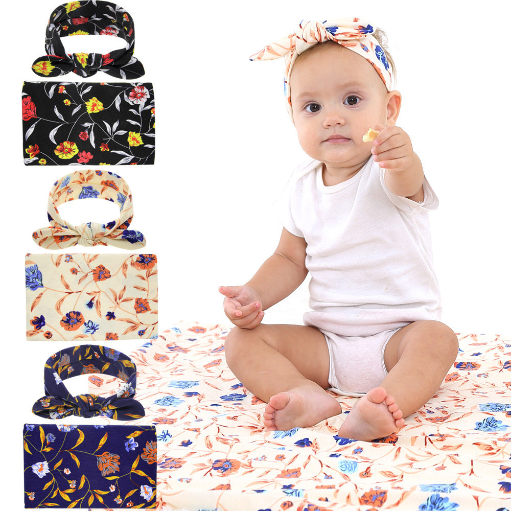 Baby sitting on a floral blanket with floral headbands 