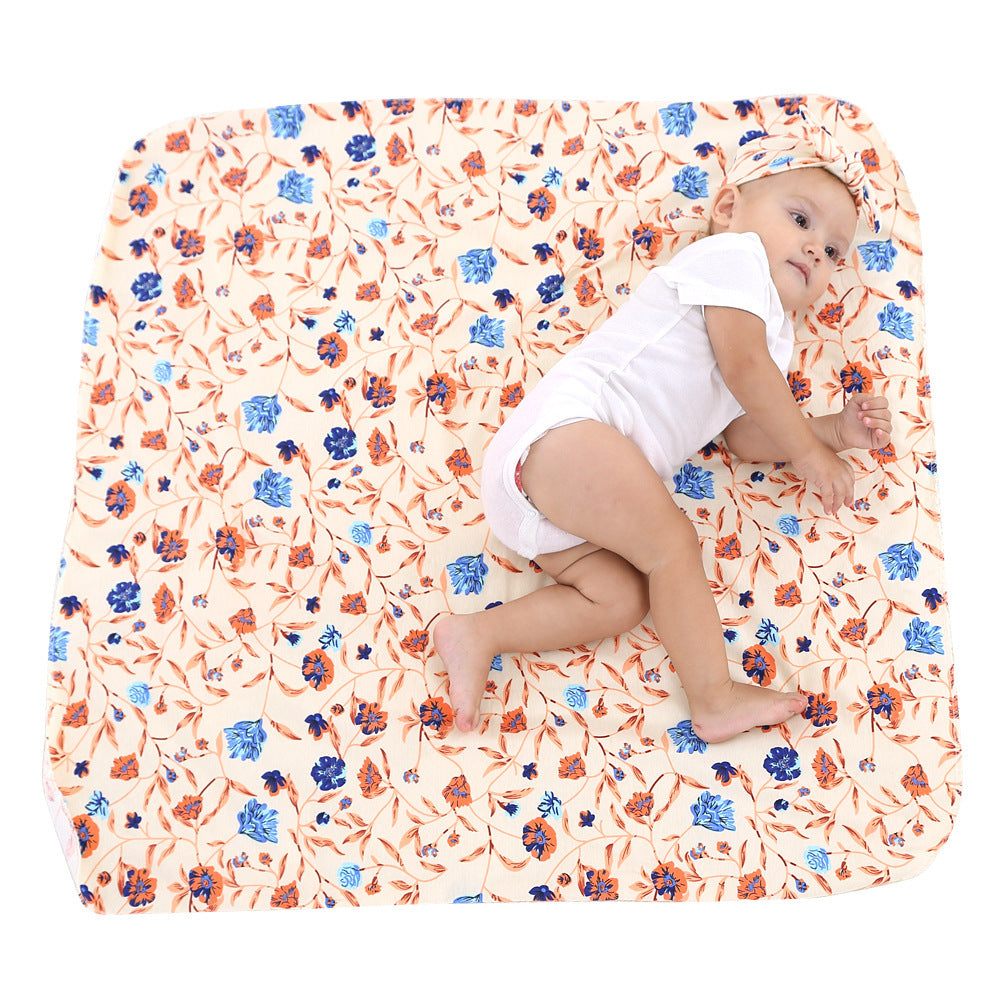Baby in a diaper sitting on a floral-patterned blanket