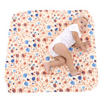 Baby in a diaper sitting on a floral-patterned blanket