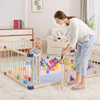 Woman and child playing with colorful balls inside a wooden playpen .