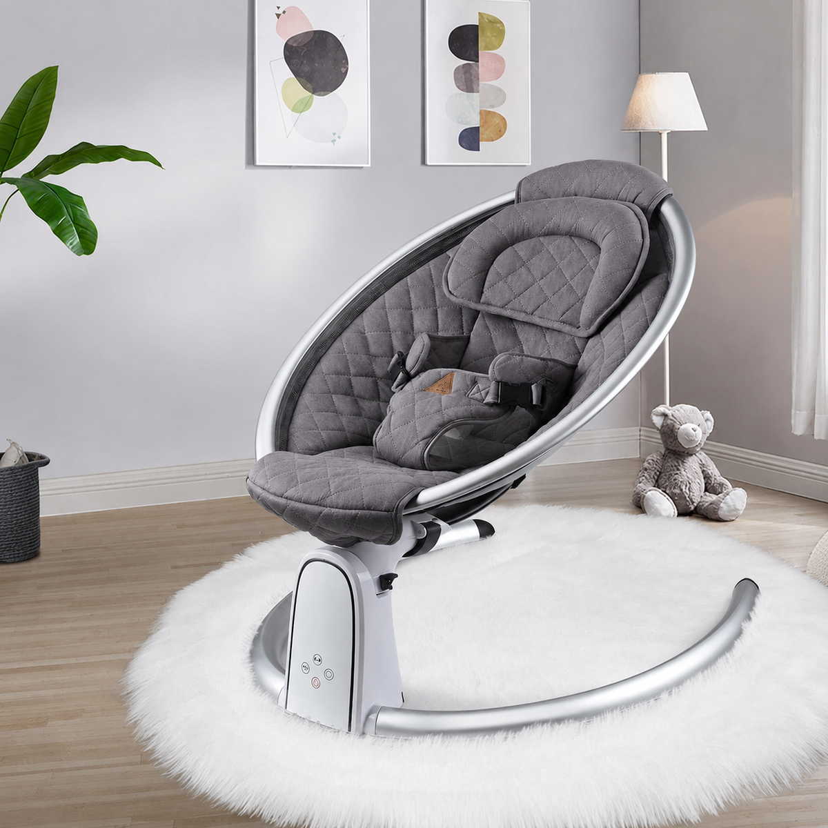 Gray baby bouncer chair in a room with a lamp and teddy bear.