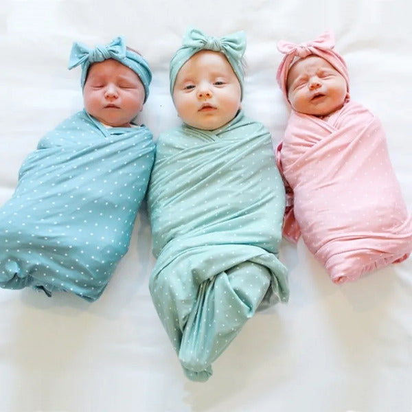 Three swaddled babies wearing colorful headbands .