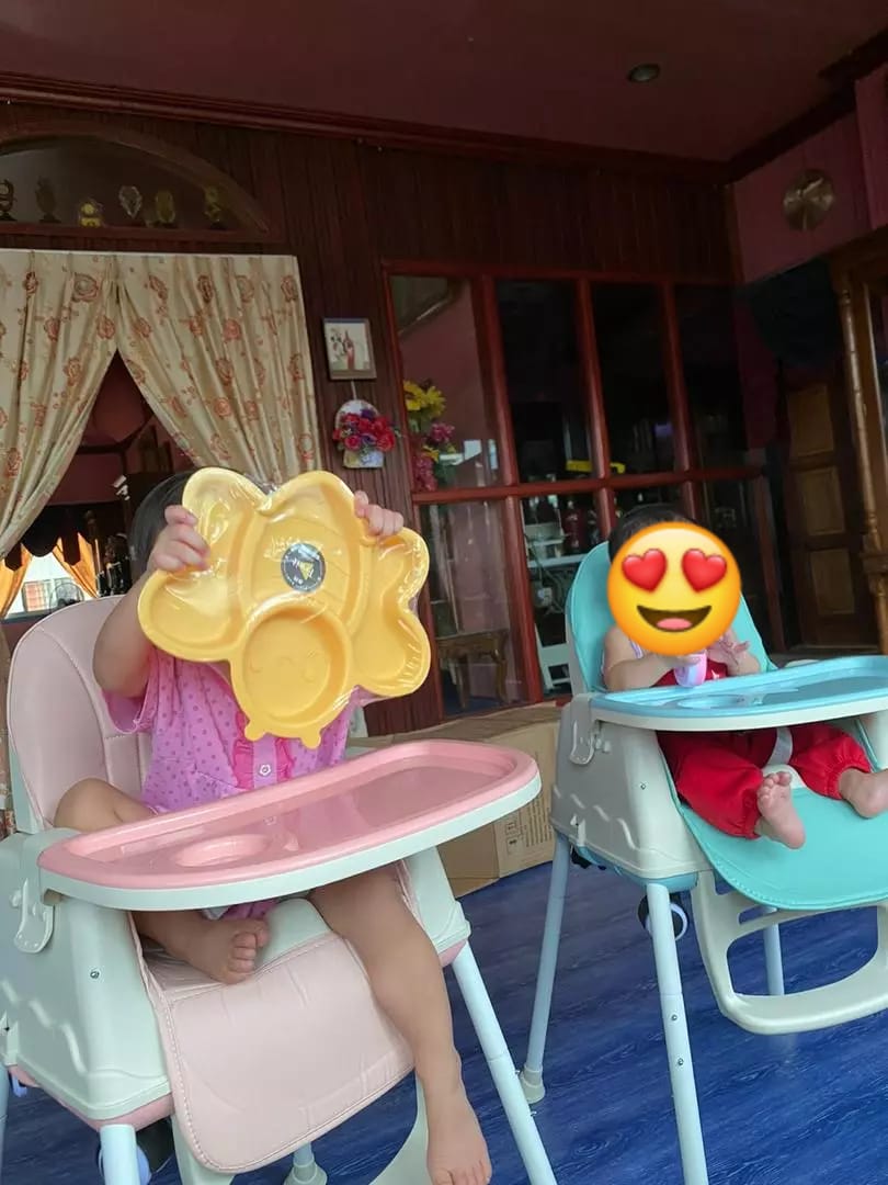 Two children in portable plastic dining baby high chairs