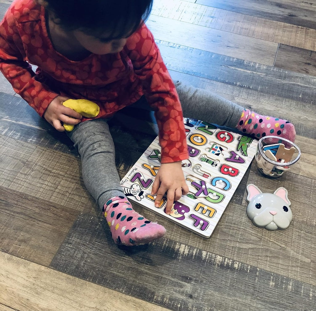 Child playing with a colorful alphabet puzzle with Melii container.
