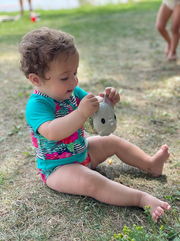 Child sitting on grass holding a Melii snack container.