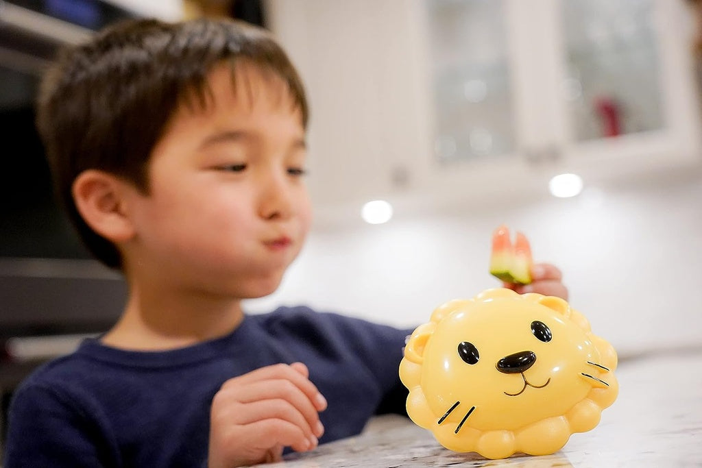 Child eating food using Melii with a lion-shaped toy .
