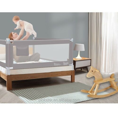 Baby being lifted by a parent over a bed with a safety rail.!