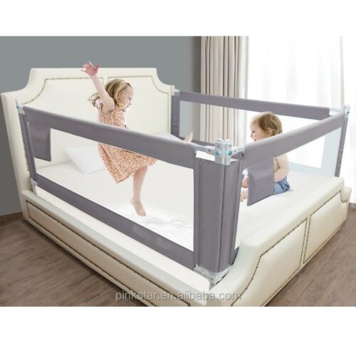 Children playing near a bed with a safety bedrail protector .