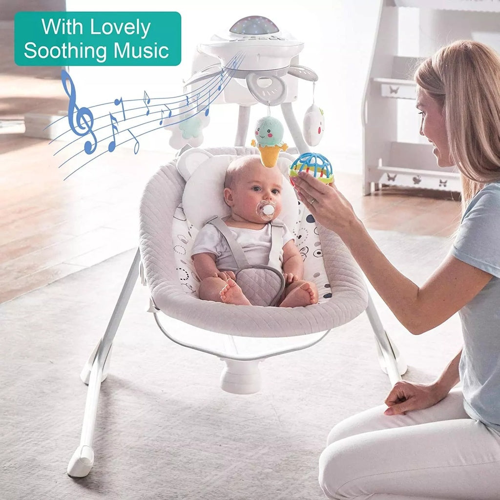 Baby in a white electric musical  baby bouncer with a woman holding a toy.