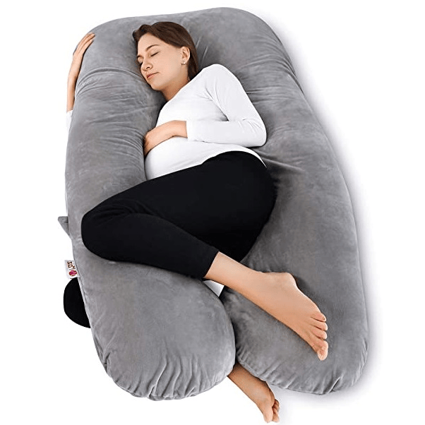 Woman lying on a pregnancy U-shaped gray pillow 