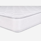 A close-up studio shot of a white quilted mattress topper or mattress corner, showing the stitched edge and textured surface .