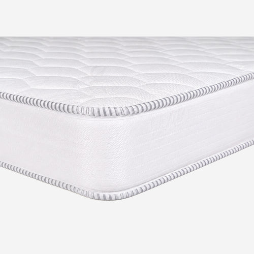 A close-up studio shot of a white quilted mattress topper or mattress corner, showing the stitched edge and textured surface .