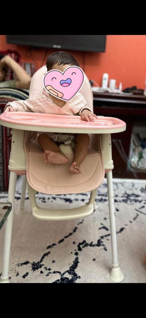 Child in a  pink baby foldable high chair 