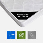Close-up of a white medicated mattress corner with a black label reading 'MEDICATED MATTRESS,' plus three feature icons below indicating softness, reversibility, and 10 cm height.