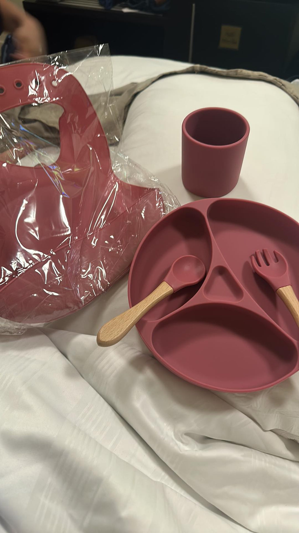 Pink silicone dining set with plate, cup, and utensils .