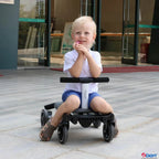 A young child sitting on a black and white  convertible rider l LT ride-on toy in front of a modern building entrance.